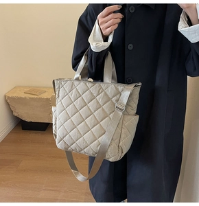 Close-up of beige quilted tote bag showing diamond stitching and functional side pocket