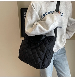Close-up of black quilted hobo bag with classic diamond stitching and wide fabric strap