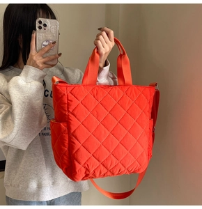 Close-up of bright orange quilted tote bag with diamond stitching and nylon texture