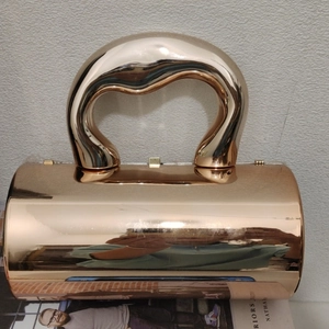 Detail einer roségoldenen Zylindertasche in Spiegeloptik mit künstlerischem gebogenem Griff