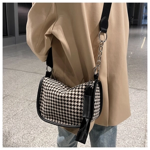 Detail of black and white houndstooth saddle bag with silver chain and wide strap