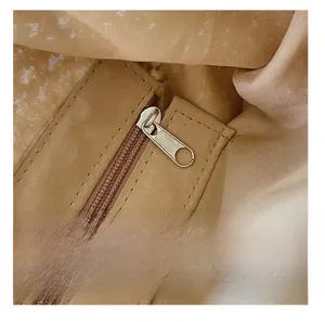 Detail view showing smooth metal zipper and neat stitching on light khaki woven bag