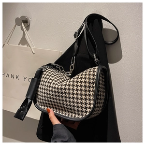 Detail of houndstooth crossbody bag with silver chain strap and leather piping edges
