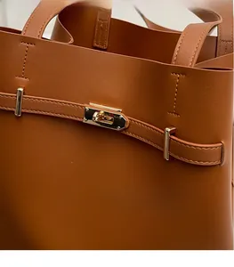 Macro shot of high-shine gold metal buckle on premium brown leather tote bag