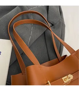 Close-up of caramel leather tote bag showing smooth dual straps and golden twist lock detail