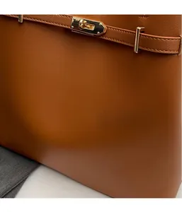 Detail of tan leather tote featuring golden metal twist lock and decorative strap