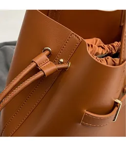 Detail of brown leather tote showing gold metal eyelets and drawstring adjustment toggle