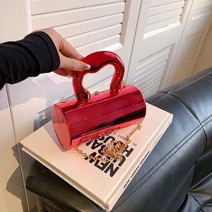 Detail der roten Zylindertasche mit herzförmigem Metallgriff und goldener Kette