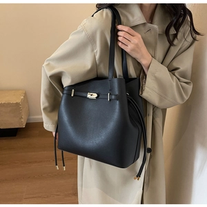 Detail of minimalist black bucket tote bag with metal buckle belt and drawstring side
