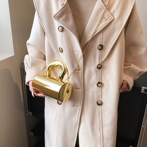 Makroaufnahme einer zylindrischen goldenen Metallhandtasche mit poliertem Spiegelglanz