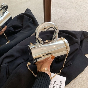Details einer silbernen zylindrischen Handtasche mit Goldkette auf schwarzem Blazer