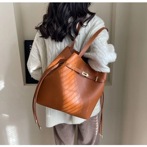 Detailed back view of a brown faux leather tote bag with drawstrings and a gold lock