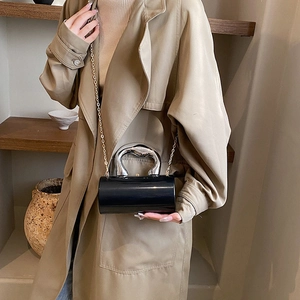 Detail der zylindrischen Handtasche mit Metallgriff und goldener Kettenriemen-Optik