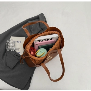 Spacious caramel brown tote bag interior showing organizational capacity and drawstring pouch
