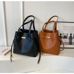 Detailed view of leather tote bags in black and brown featuring gold metal clasps