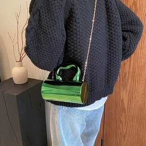 Details der smaragdgrünen metallischen Zylindertasche mit Wellengriff und Kette