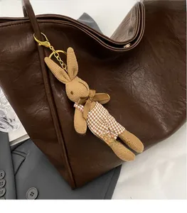 Nahaufnahme eines handgestrickten Kaninchen-Anhängers in Khaki an einer braunen Tasche