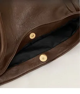 Details einer dunkelbraunen Ledertasche mit hochwertiger goldener Magnet-Metallschnalle