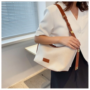 Detail einer Canvas-Schultertasche mit braunem Lederbesatz und goldenen Metallelementen