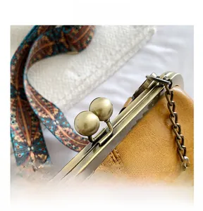 Detail of yellow leather handbag with metal clasp and patterned wide strap