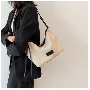 Detail der kontrastierenden Canvas-Hobo-Tasche mit schwarzem Lederbesatz an einem Model