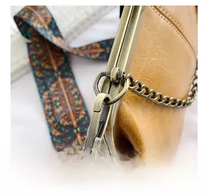 Detail of vintage brown leather bag showing bronze hardware and ethnic strap
