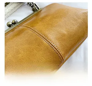 Detail showing precise stitching and litchi texture on brown leather crossbody bag