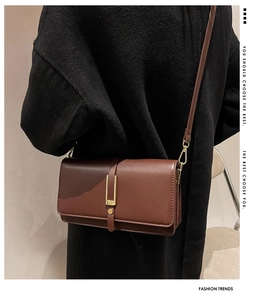 Dettaglio laterale di borsa a tracolla vintage in pelle marrone con fibbia dorata