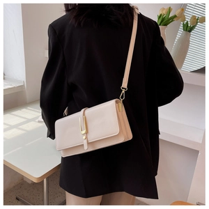 Dettaglio borsa a tracolla beige crema con fibbia dorata su un abito nero elegante