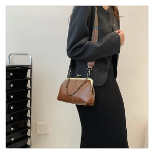Detail of vintage brown leather kiss-lock bag with bohemian wide shoulder strap