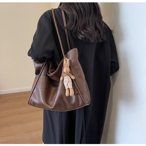 Detail einer dunkelbraunen Ledertasche mit einem niedlichen Plüschhasen-Anhänger