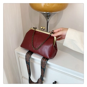 Detail of burgundy PU leather clutch with vintage frame and ethnic pattern strap