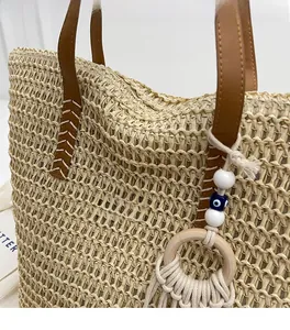 Detail of hand-woven straw tote with leather straps and bohemian beaded charm accessory
