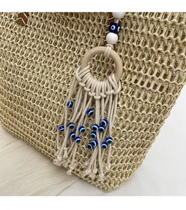 Detail of bohemian evil eye charm with tassels on a woven straw tote bag