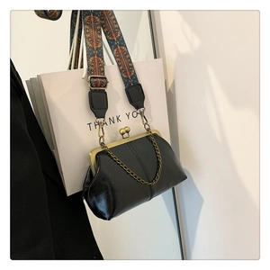 Detail of black vintage kiss-lock bag with bohemian wide strap and bronze chain