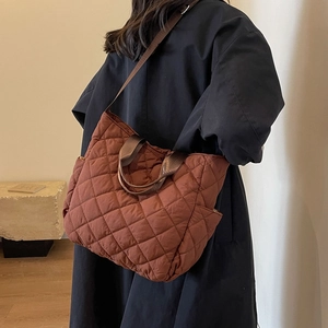 Brown quilted lattice tote bag with dual straps shown in a minimalist interior setting