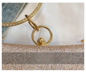Détail de la pochette champagne doré avec poignée en métal strassé et texture pailletée