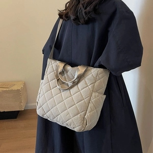 Padded beige quilted tote bag with wide straps shown on a model for casual daily use