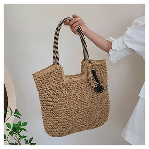 Woven straw tote bag with striped handle and dual-color tassel on a neutral background