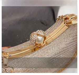 Detailed shot of the champagne glitter evening bag featuring pearl and rhinestone metal clasp