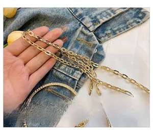 Détail d'une bandoulière en chaîne dorée avec une boucle ronde ornée de strass brillants