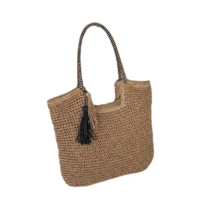 Handwoven straw tote bag with black and white striped shoulder strap and tassel