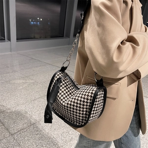 Houndstooth crossbody bag with black leather trim and decorative silver chain strap