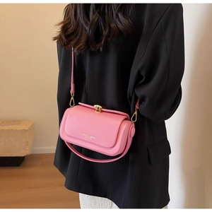Sac bandoulière en cuir rose mat avec fermoir doré sur une veste de blazer noire