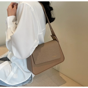 Detail of tan leather shoulder bag with adjustable metal buckle on a shoulder strap