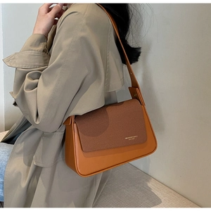 Detail of vintage brown textured crossbody bag showing mixed leather and woven fabric panel