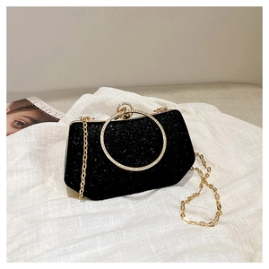 Détail d'une pochette de soirée à paillettes noires avec poignée anneau dorée et strass