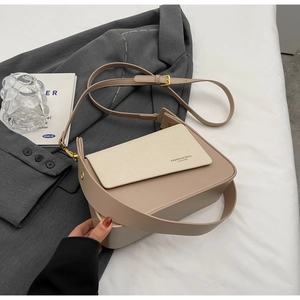 Detail of two-tone khaki and beige crossbody bag with textured flap and fashion lettering