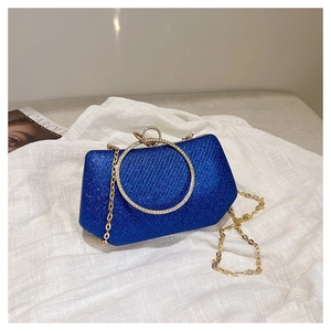 Détail d'une pochette à paillettes bleu roi avec poignée anneau dorée et bandoulière chaîne