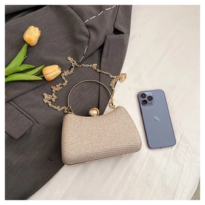 Detail of gold sequin evening bag featuring a pearl clasp and round metal handle